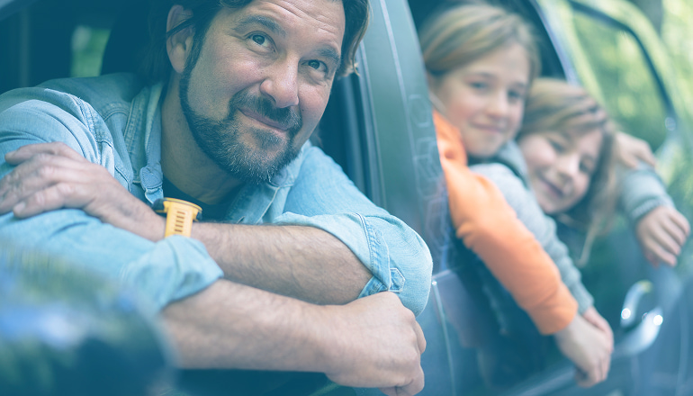  Padre e hijos asomados por la ventana de un coche, representando la diferencia en indemnizaciones por accidentes entre adultos y menores y la importancia de proteger sus derechos.